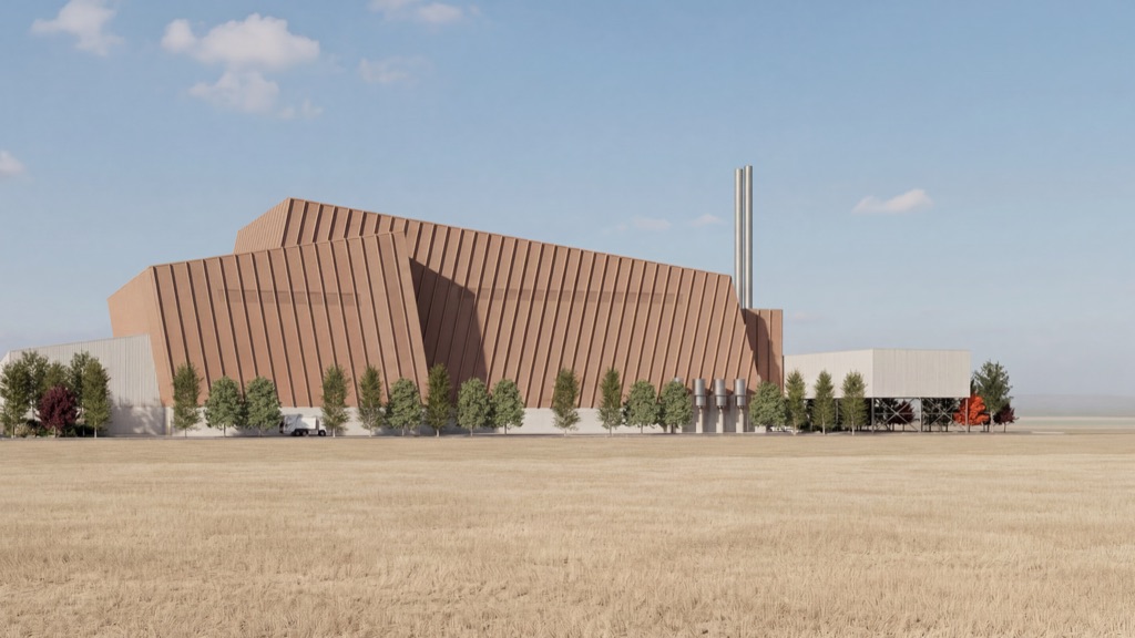 Edificio principal del Centro Ambiental Jarama, con fachada de lamas de cobre, cubiertas inclinadas y dos chimeneas de acero, rodeado de árboles en medio de un campo de cereal.